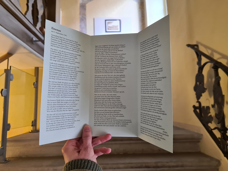 Frau hält Flyer Gedicht Ilmenau von Goethe in den Händen im Museum